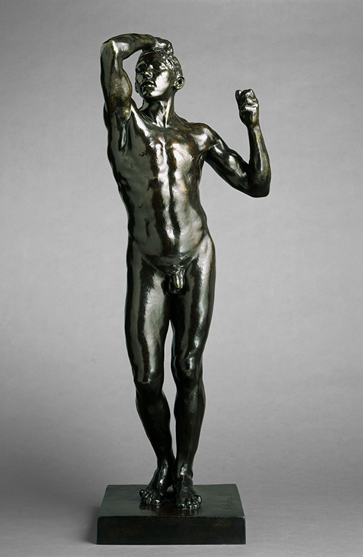 a bronze statue of a nude young man posing confidently with his right hand on his head, elbow forward, and his left hand raised in a shoulder-level fist