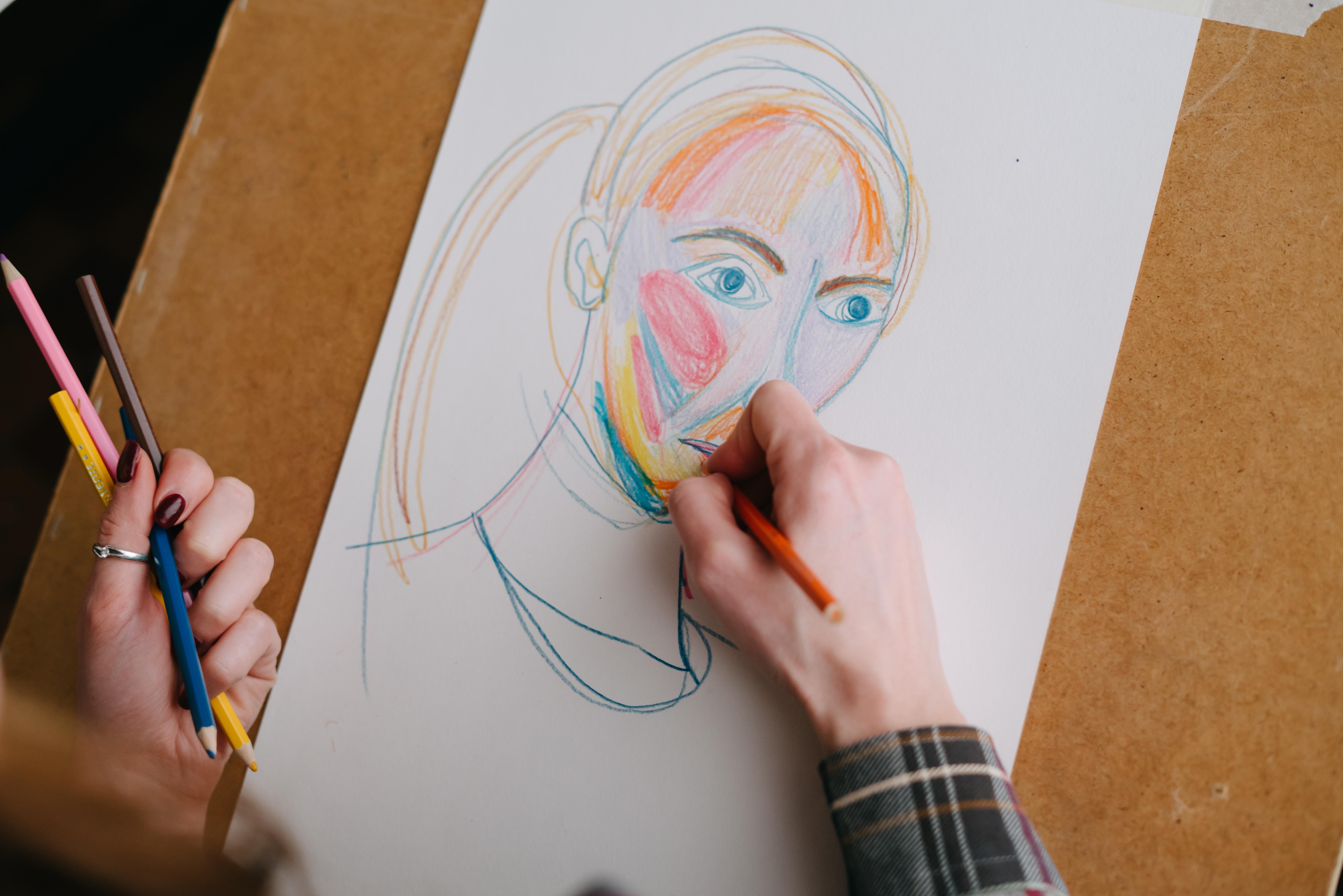 A person adding detail to a drawing of a face