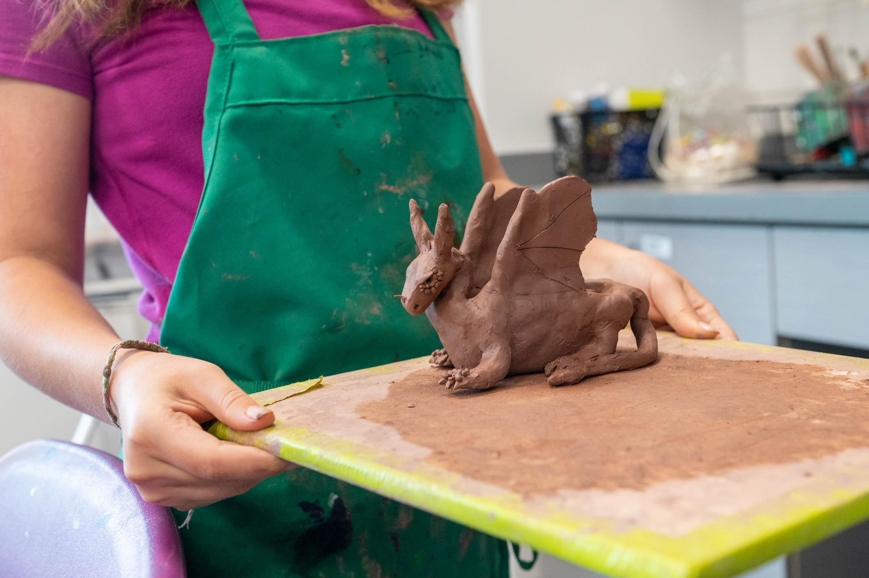 a camper holds the dragon she made from clay