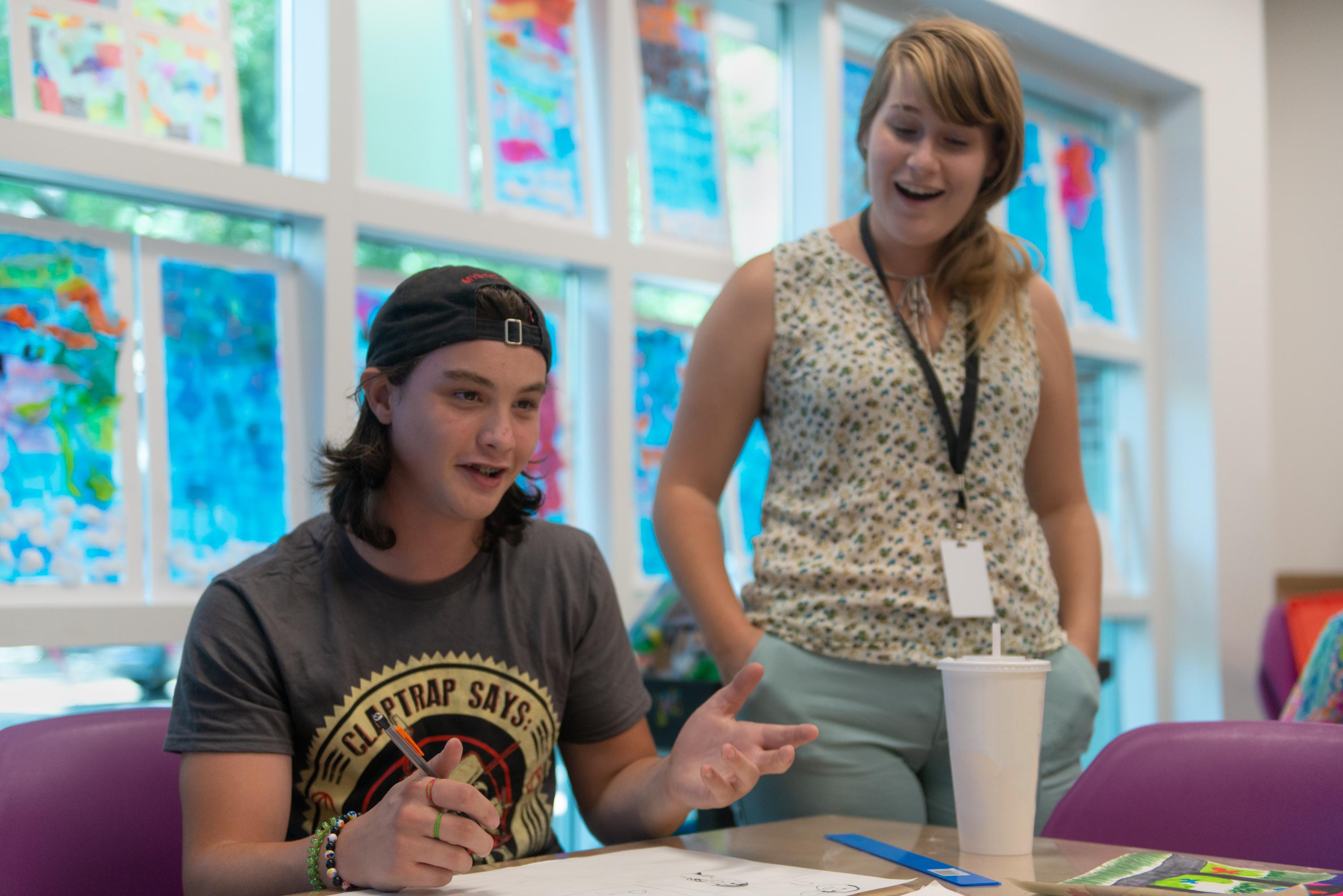 a teen discusses his work with an instructor