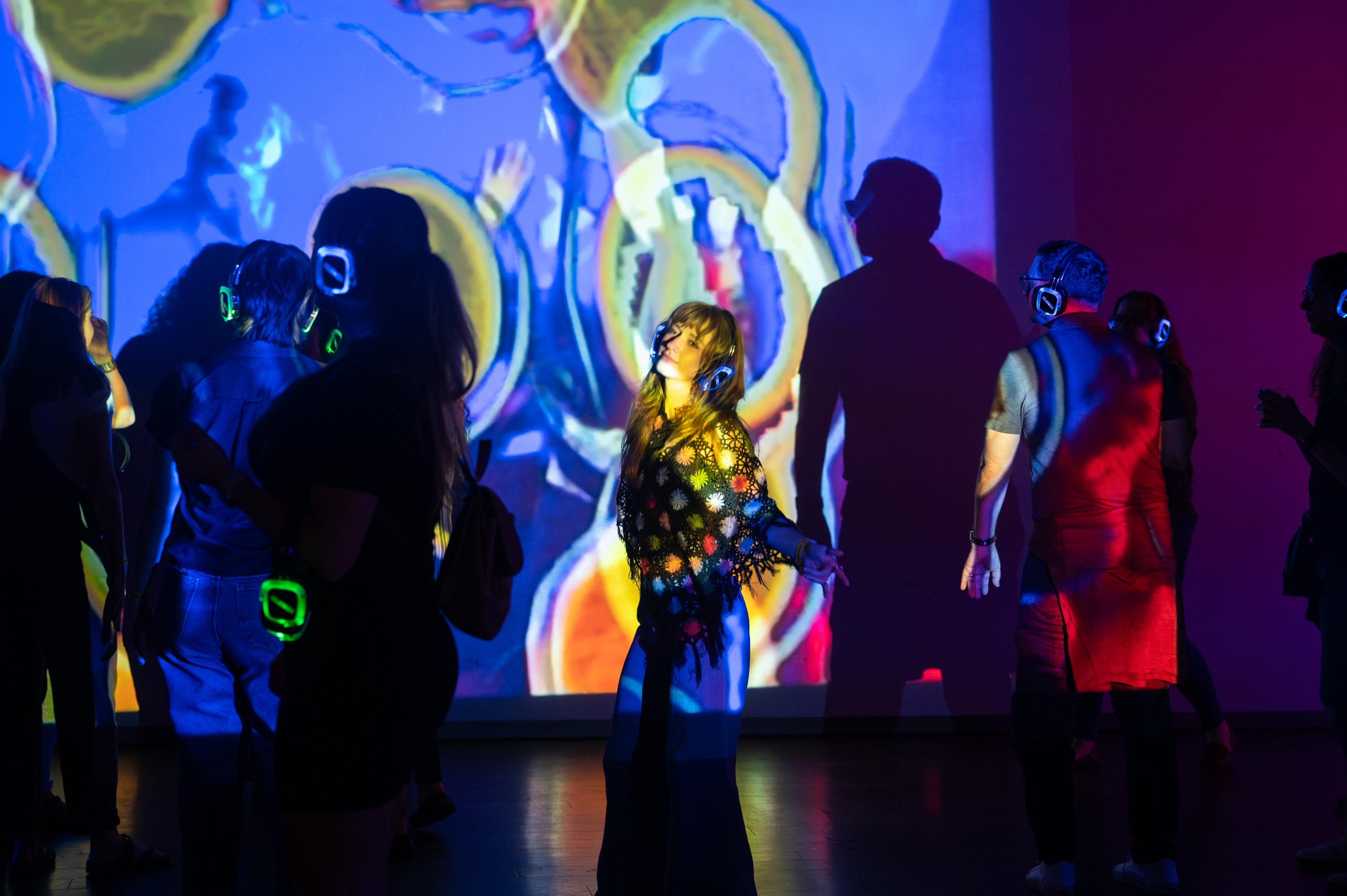 visitors dancing in a space covered in patterns of light and color